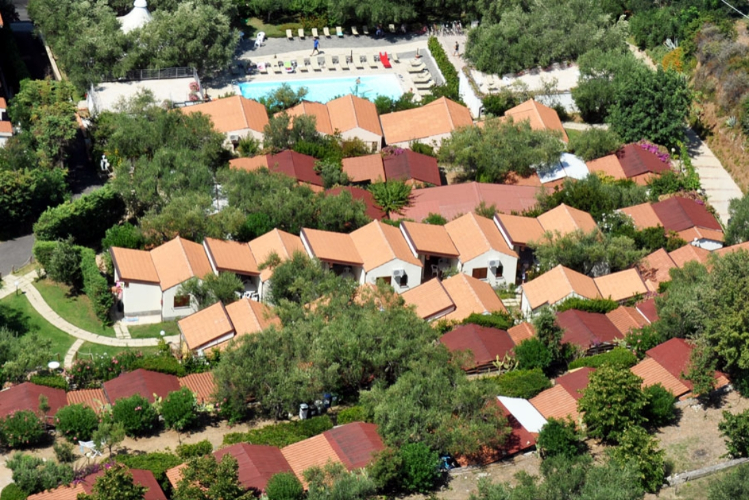 Aerial view of bungalows with a pool surrounded by trees.