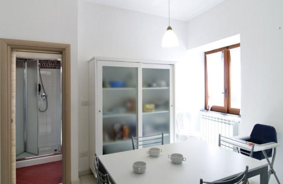 Sala da pranzo luminosa con tavolo, sedie e vista su un bagno con doccia.