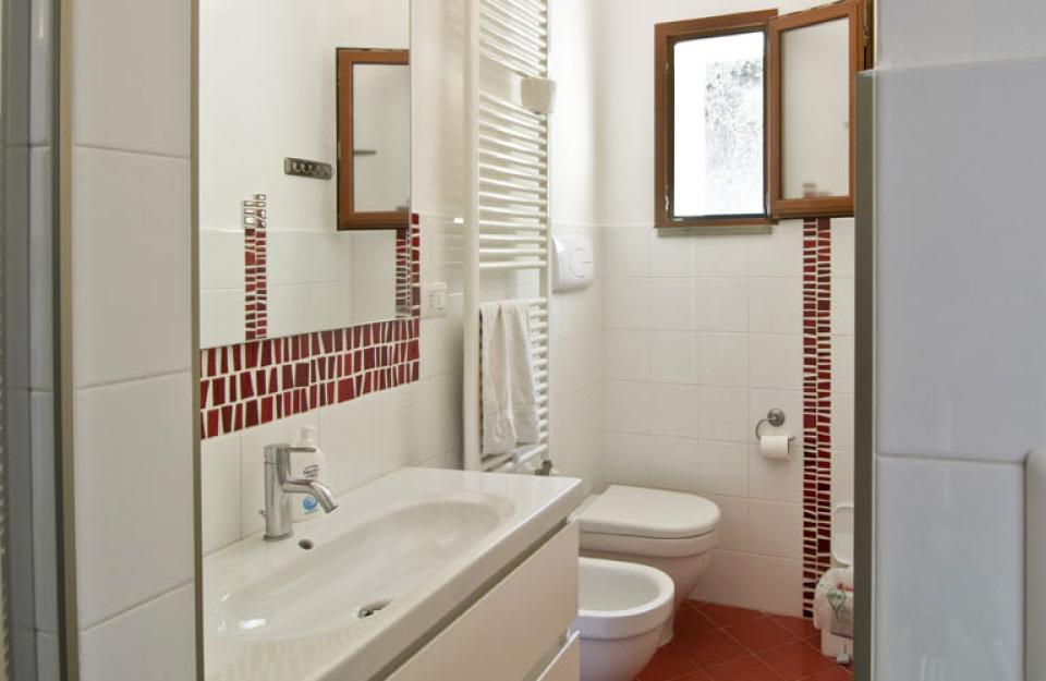 Bagno moderno con piastrelle rosse e bianche, finestra e sanitari.