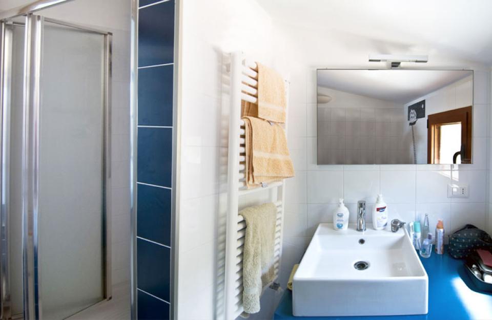 Bagno moderno con doccia, lavabo e specchio ampio.